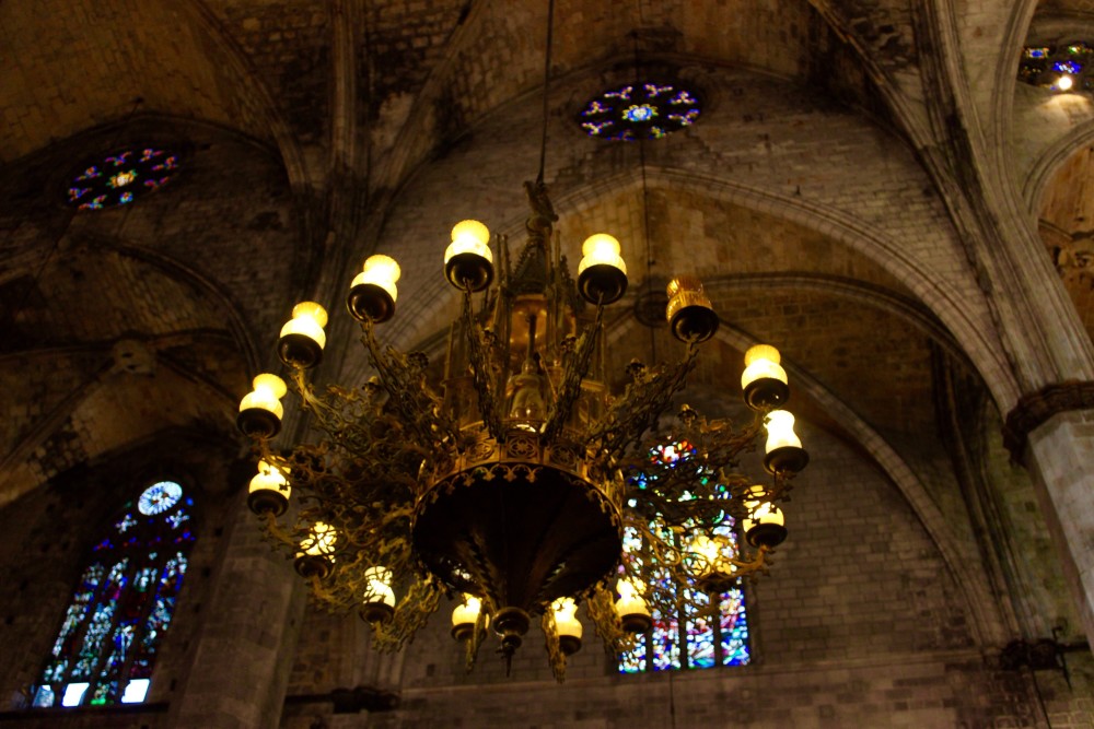 Barcelona's Gothic Quarter, dark cathedral with stained glass windows and chandelier 