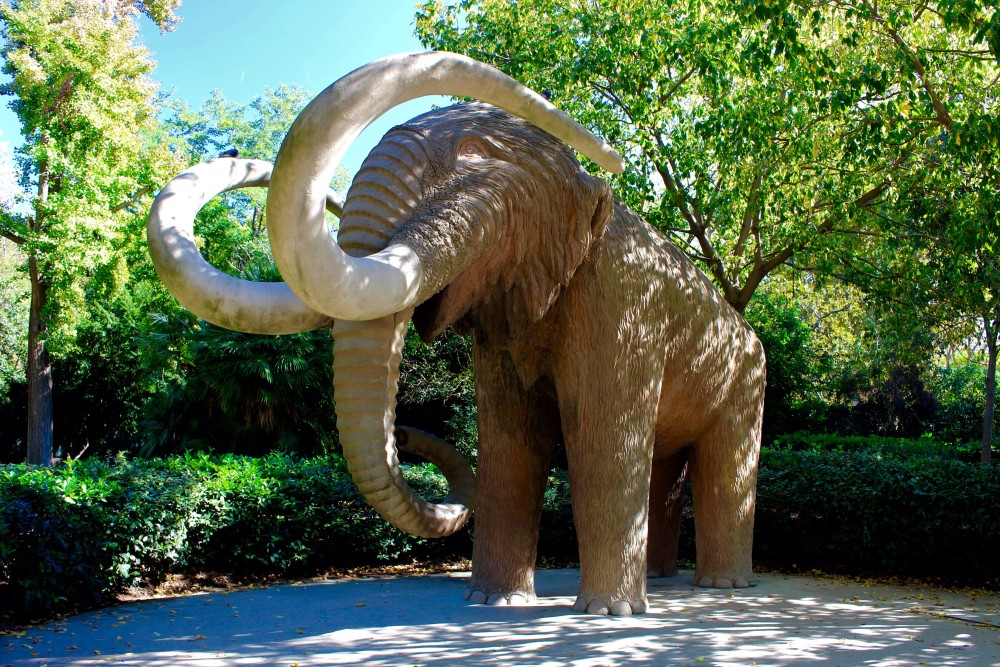 Mammoth statue in the middle of lush green trees in Parc de la Ciuteadella in Barcelona, Spain