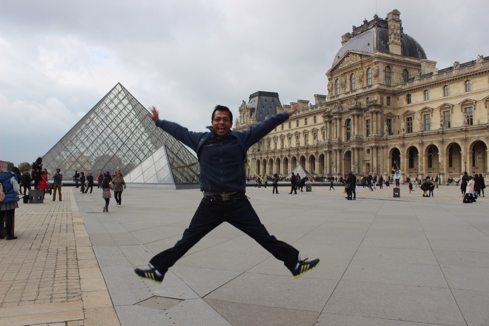 Jumping in front of the glass pyramid at the Louvre in Paris, France