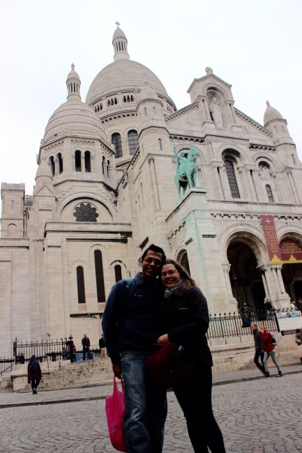 A couple standing in front of the white stone Sacre-Coeur in Paris, France