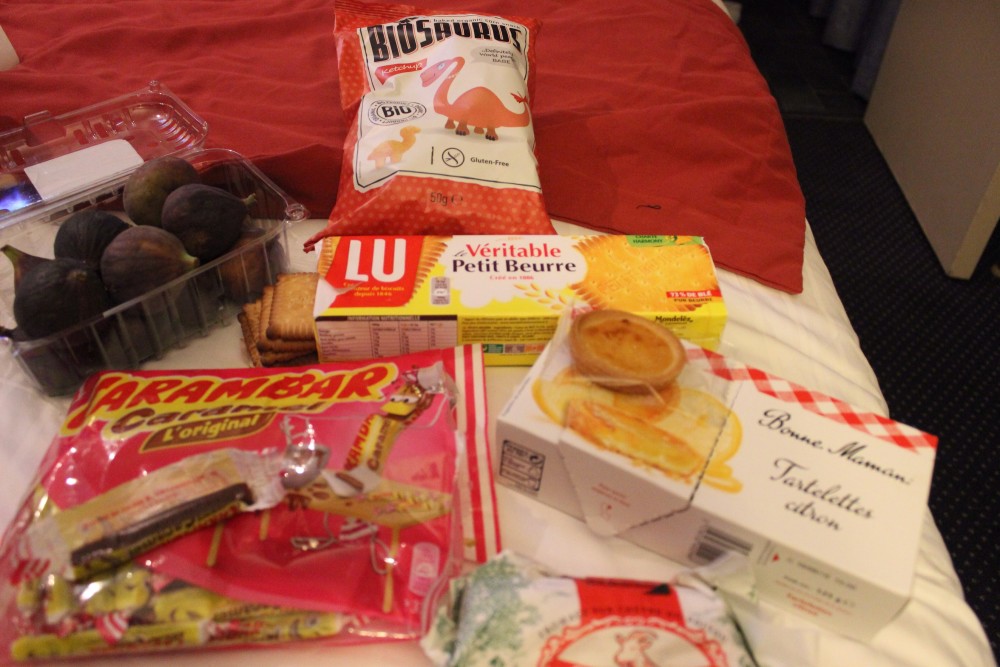 An assortment of snacks on a hotel bed in Paris, France
