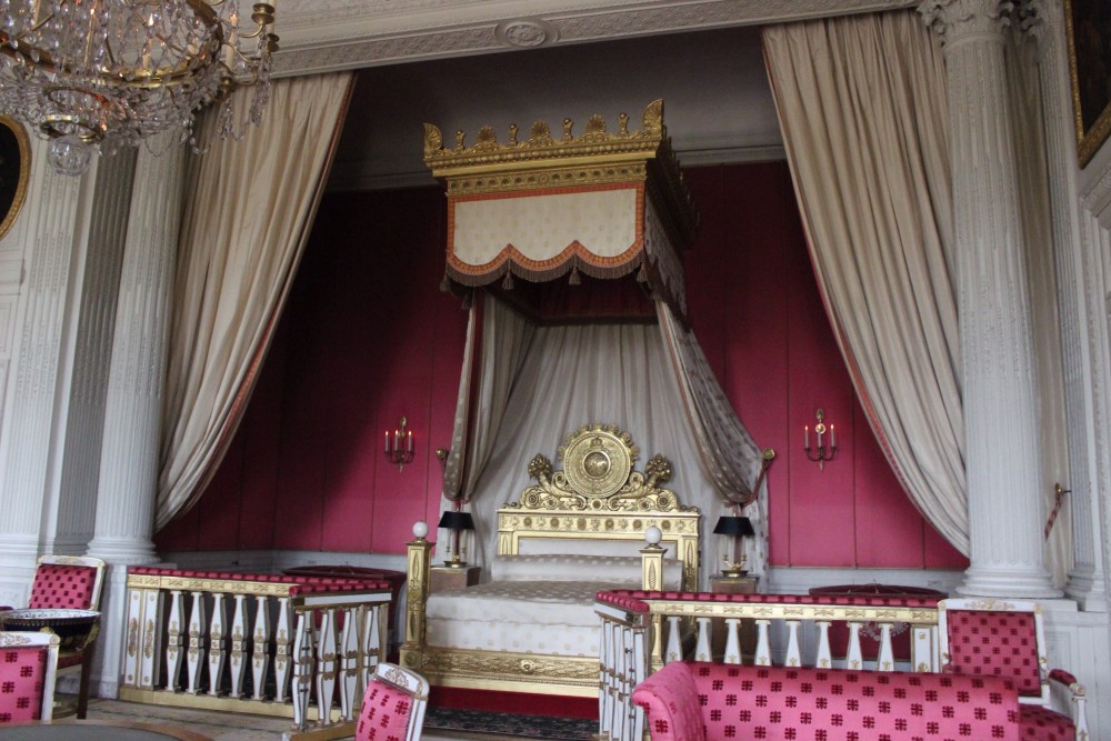Luxurious Royal bed with purple walls and cream drapes at Versailles