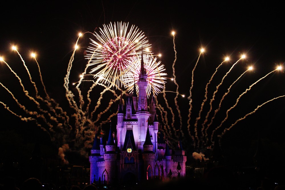 Magic Kingdom fireworks behind the castle lit up in purple