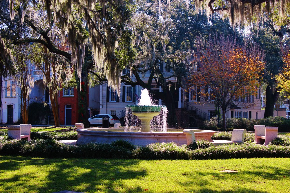 Savannah Squares with the sun shining on a fountain surrounding by trees with Spanish moss