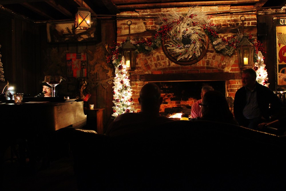 Basement bar decked out for the holidays with a fireplace and old lady playing the piano