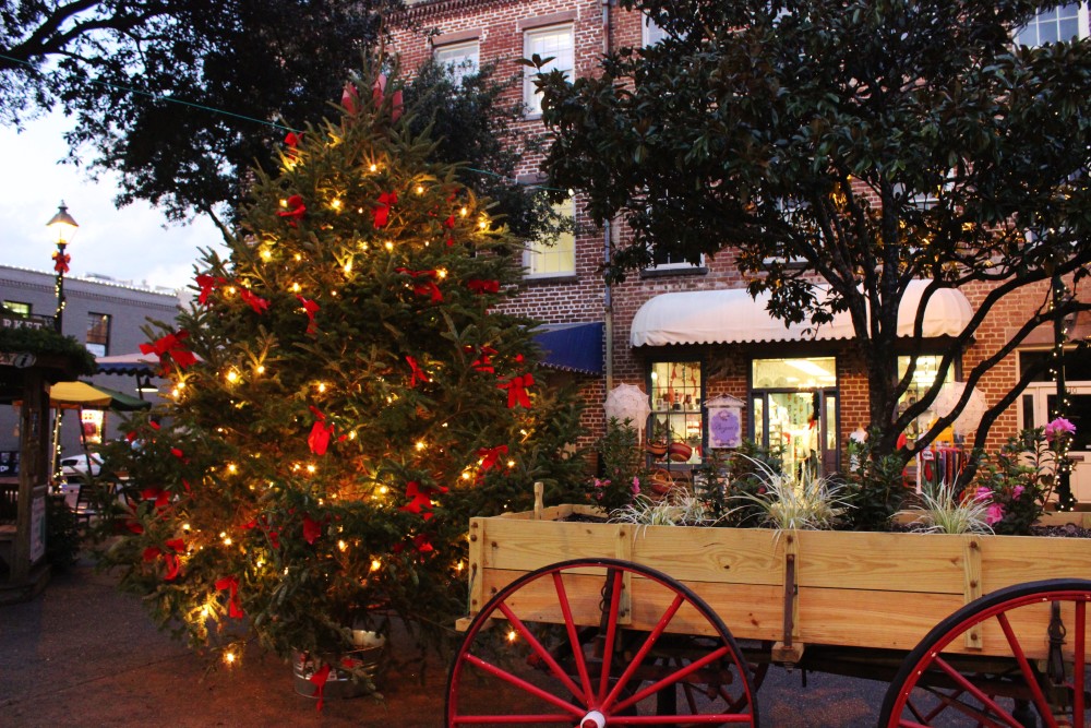 Savannah, GA decorated for Christmas with a pine tree full of red bows and lights and a wagon with flowers