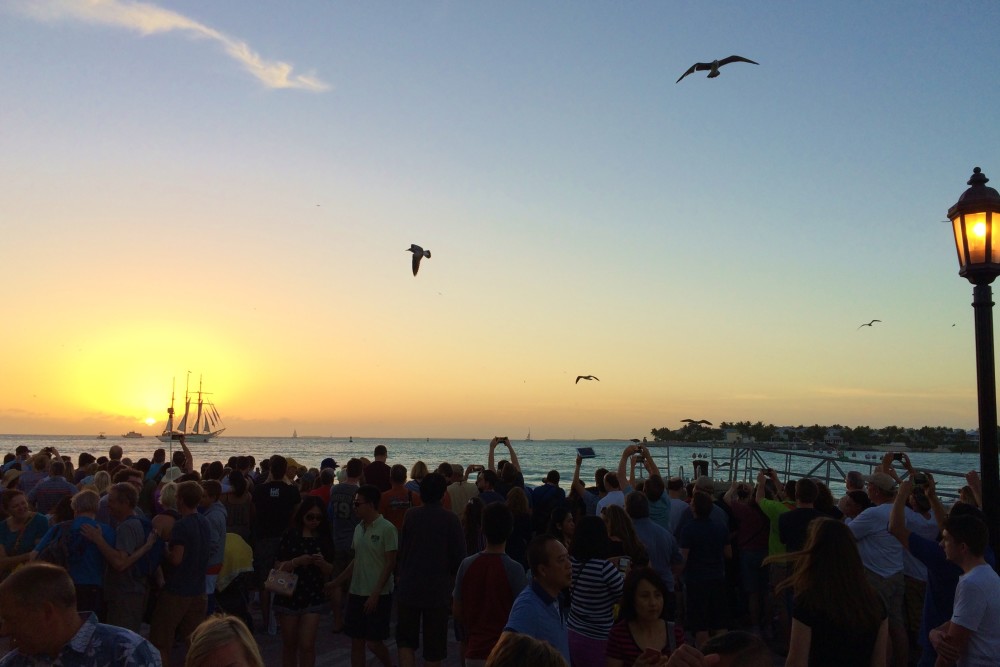Key West Sunset, crowd watching the sunset with a boat sailing by