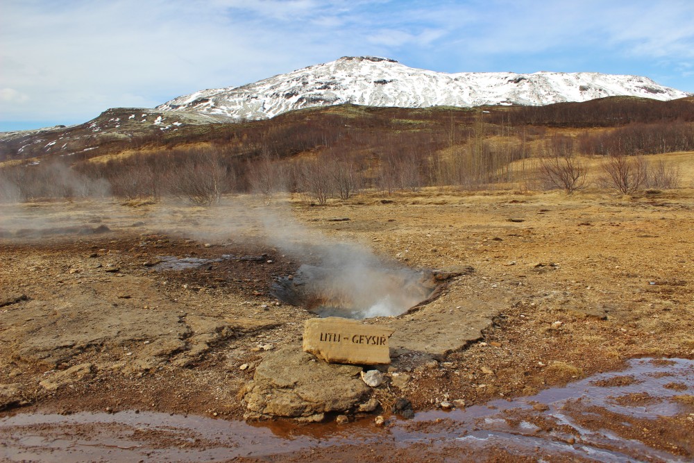 cute Litli Geysir with snow capped mountain in the background